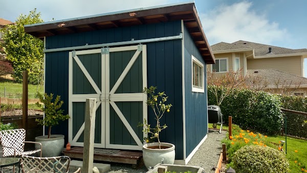 Compact custom outbuilding with barn-style doors, painted siding, and a finished roof