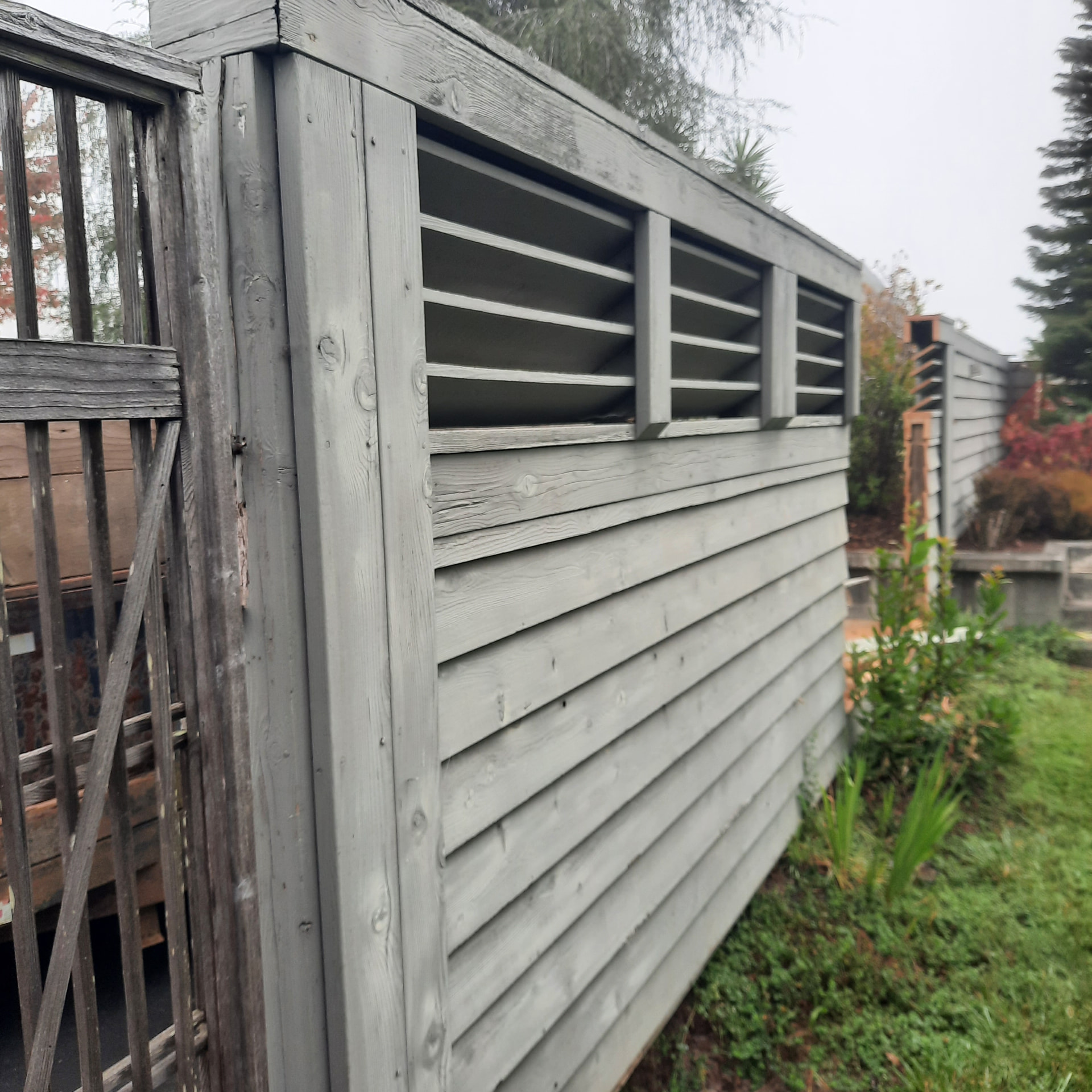 Aging louvered courtyard screen and weathered lightweight gate before rebuilding