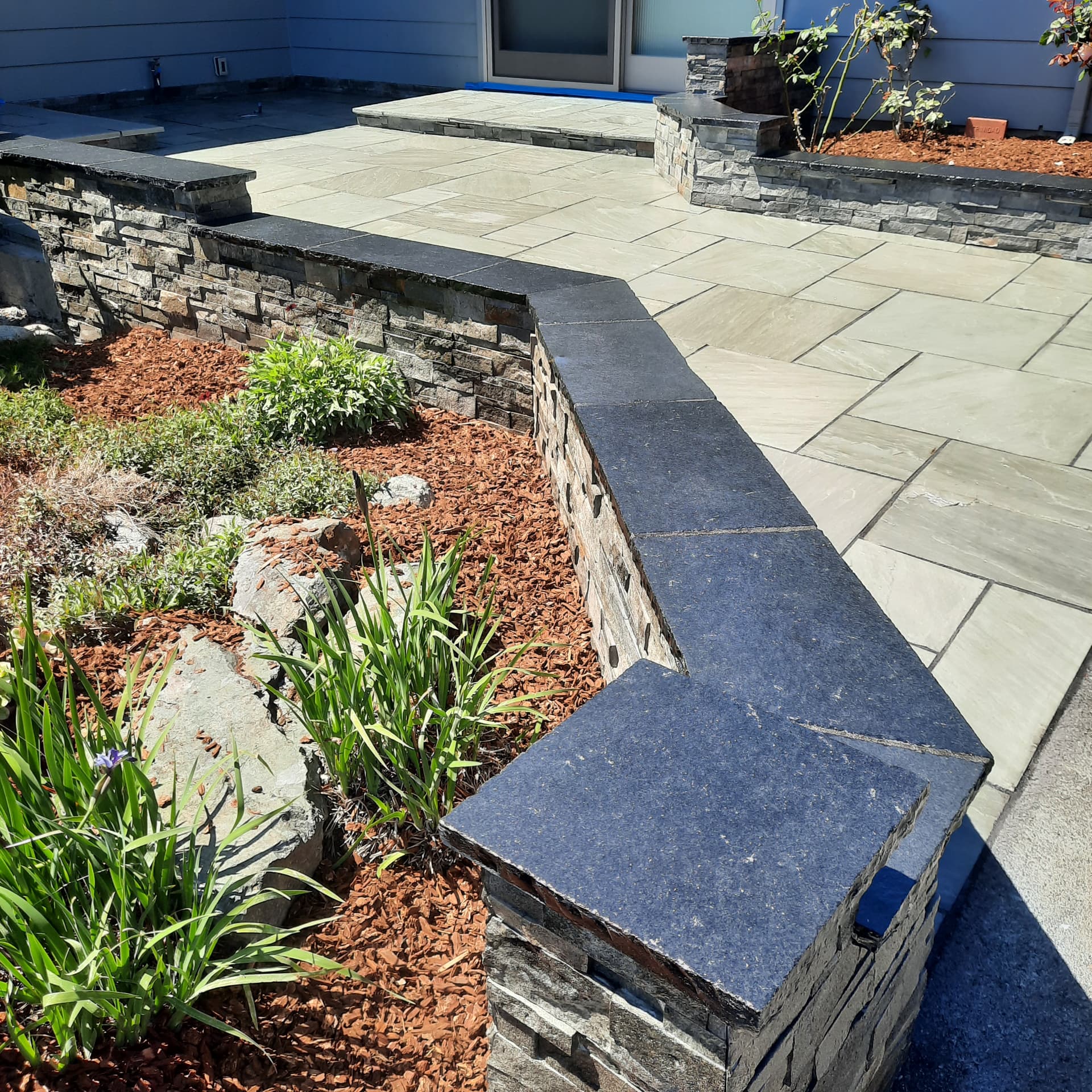 Close view of finished paving beside a stacked-stone wall with contrasting dark stone caps