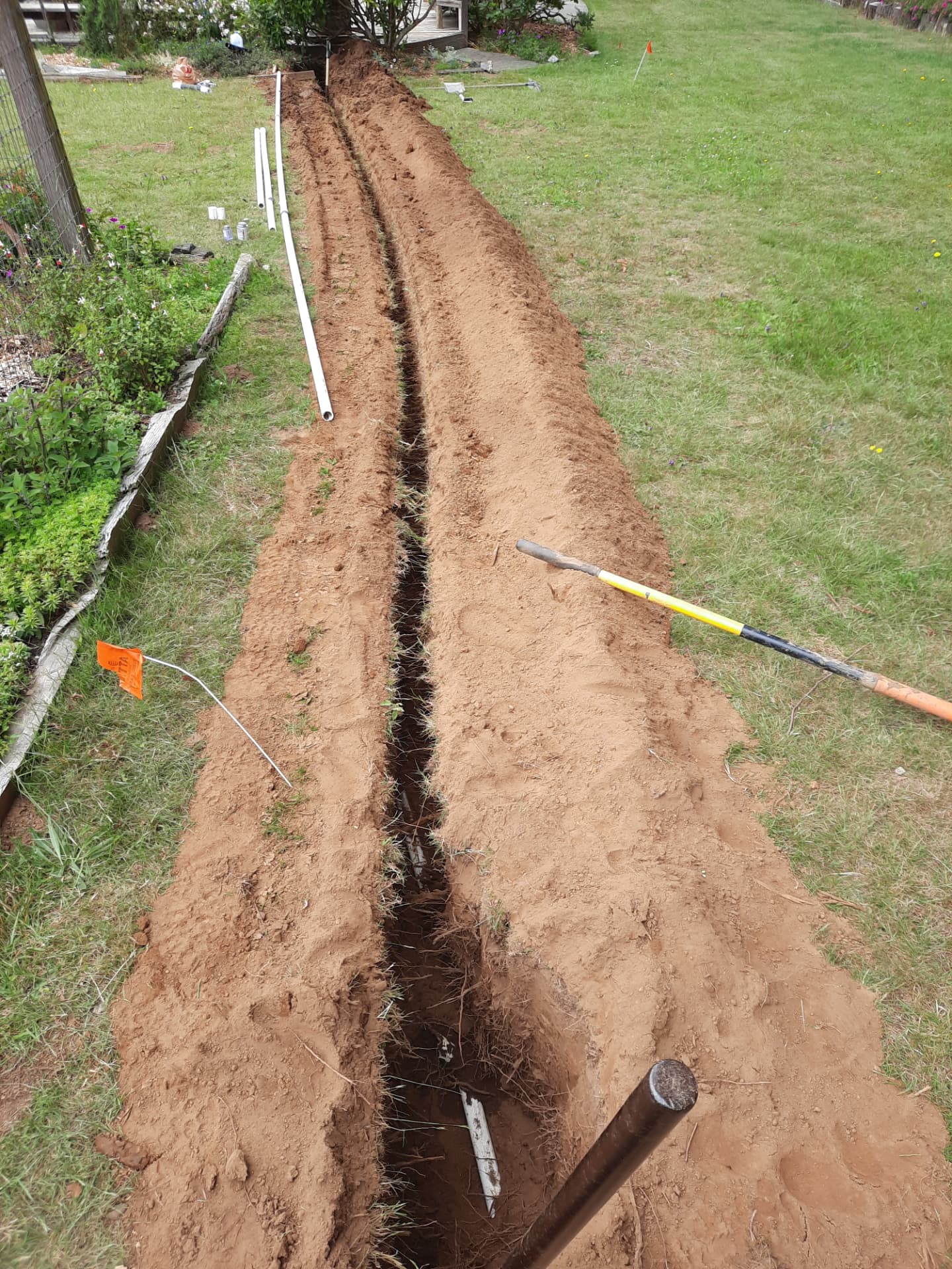 Open irrigation trench documenting buried pipe routing before backfill