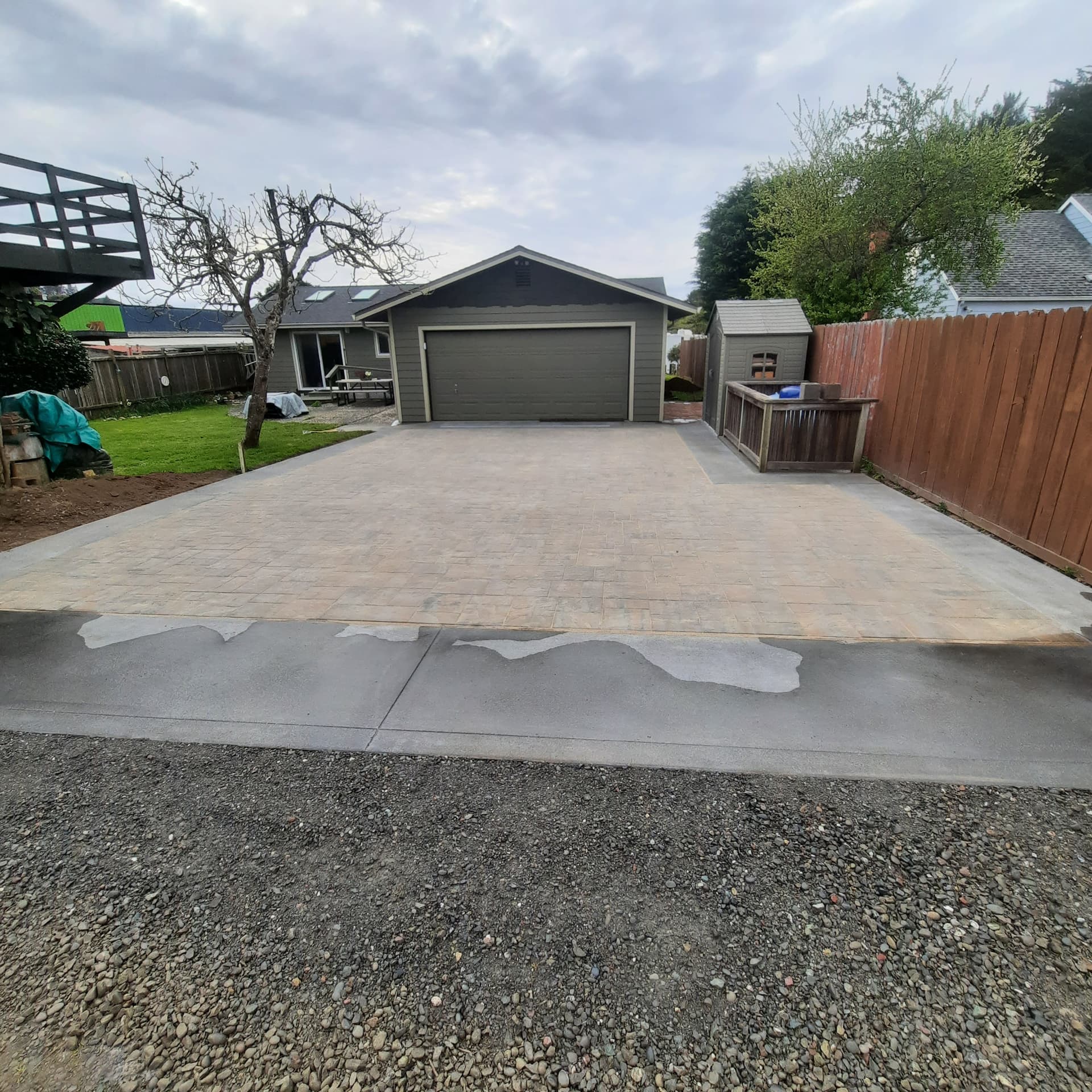 Wide view of the finished paver driveway leading to the garage, tying into the rest of the property
