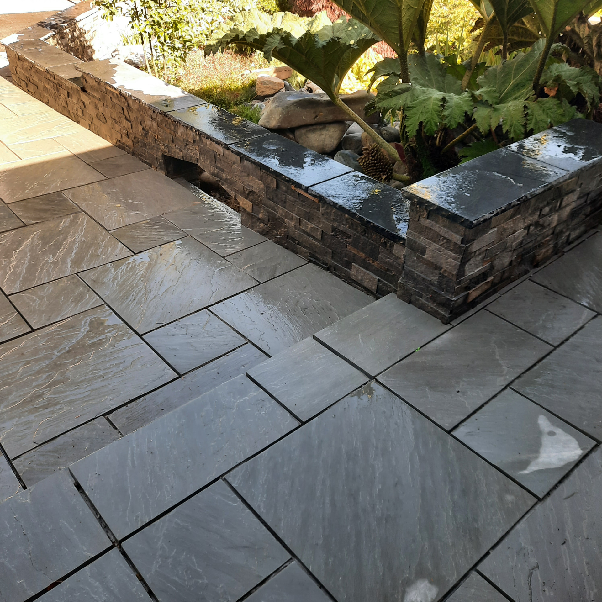 Finished retaining wall and planting edge where stone paving meets the surrounding garden