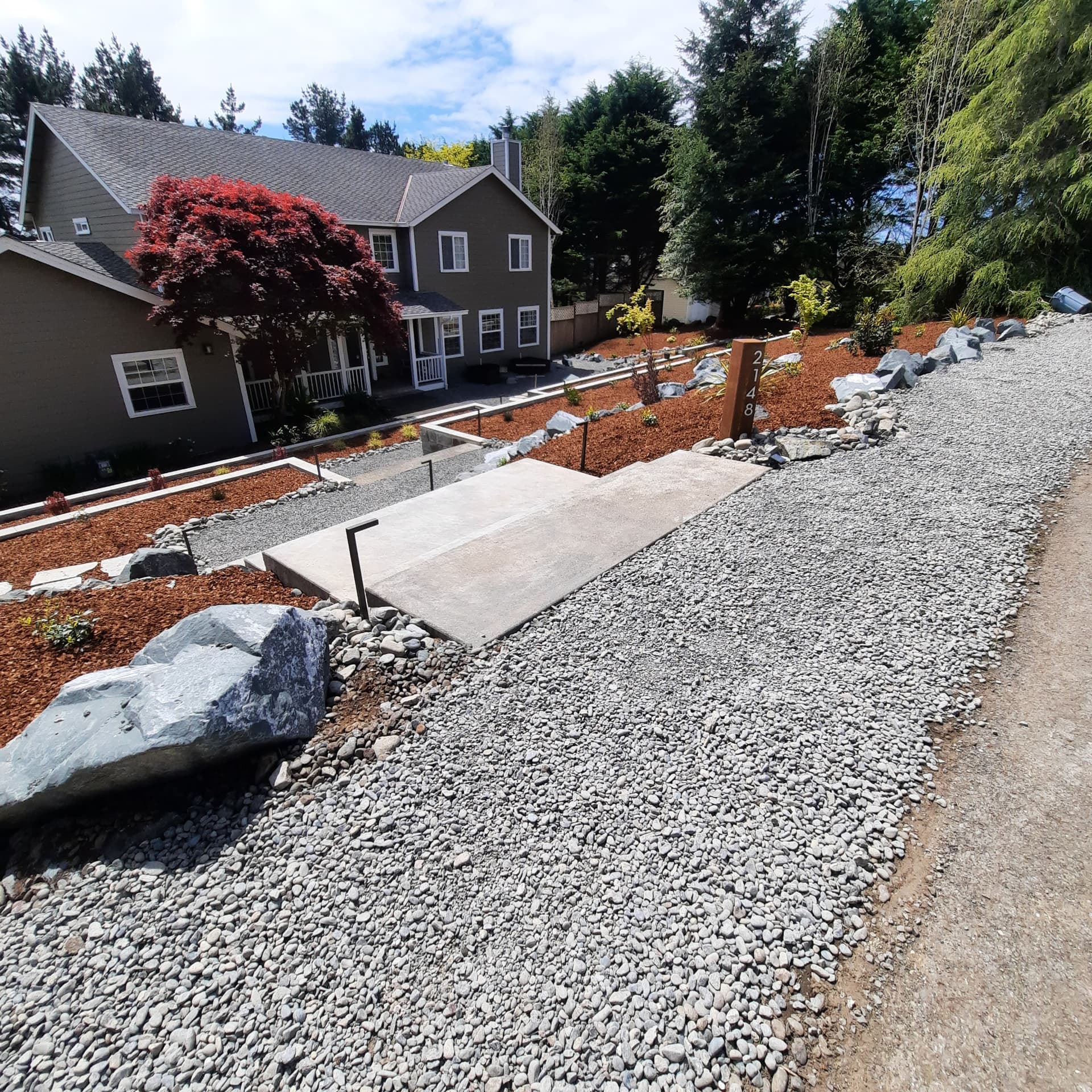 Renovated Terra Vista garden with new stairs, capped wall, steel planting beds, and fresh planting under a mature maple