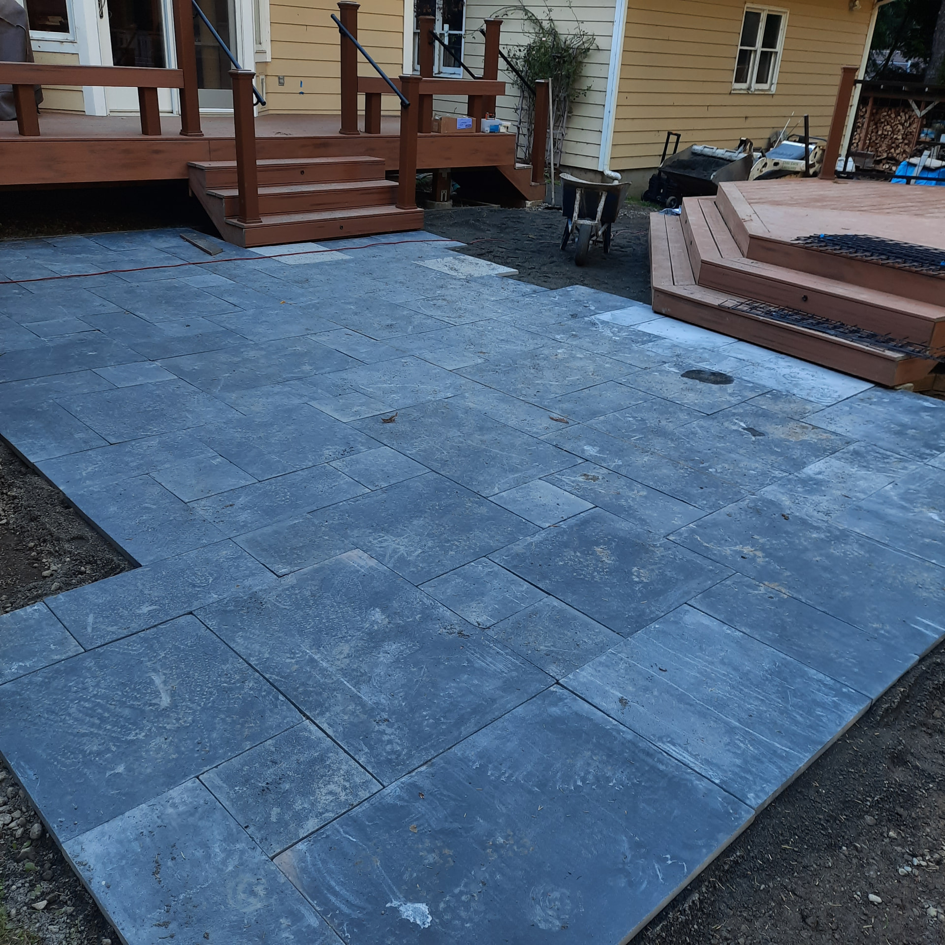 Slate patio laid between the finished house deck with railing and the new composite deck stairs