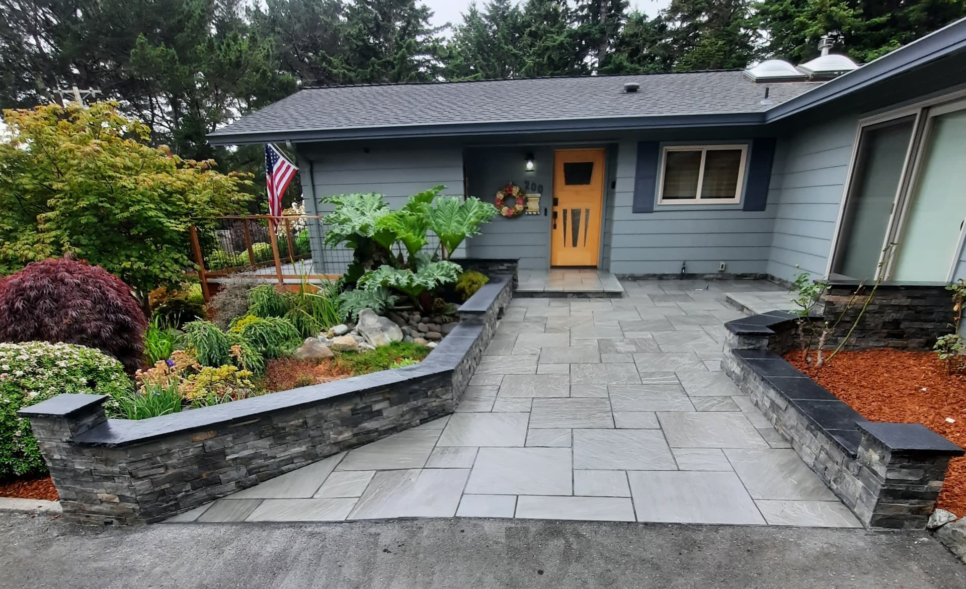 Finished stone entry courtyard with walls, paving, and planting at the front of a home